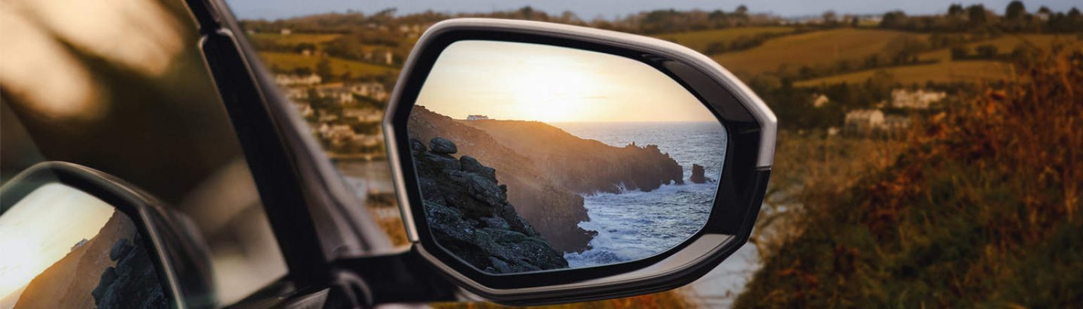 Cornwall coastline in a BMW i5 wing mirror.
